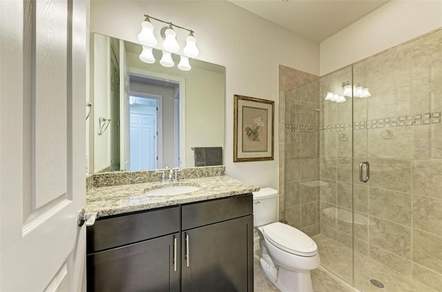 bathroom with toilet, vanity, and a shower with door