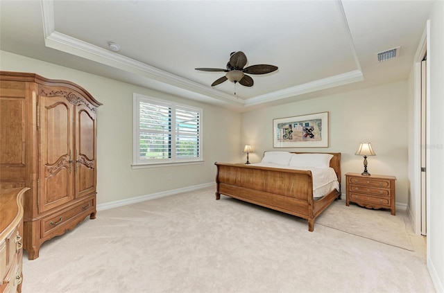 bedroom with ceiling fan, light colored carpet, and a tray ceiling