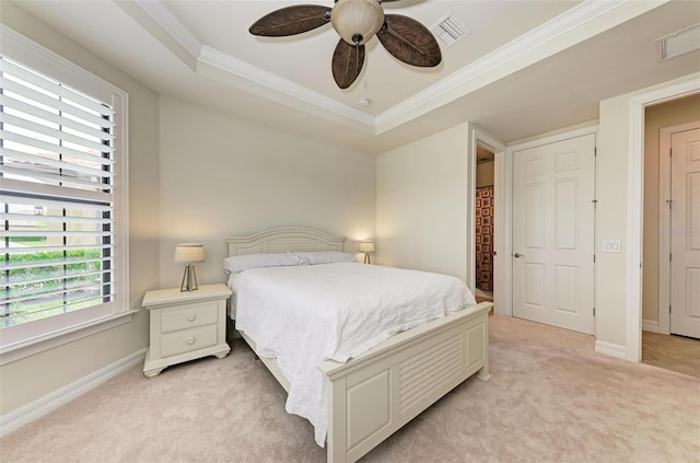 bedroom featuring ceiling fan, crown molding, a tray ceiling, and light carpet