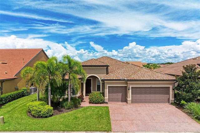 mediterranean / spanish house featuring a front yard, central AC unit, and a garage