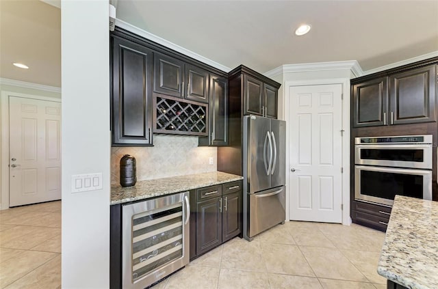 kitchen with light stone countertops, appliances with stainless steel finishes, wine cooler, light tile patterned floors, and crown molding