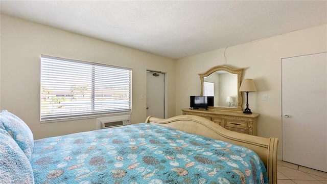 bedroom with light tile patterned floors, a textured ceiling, and a wall mounted AC