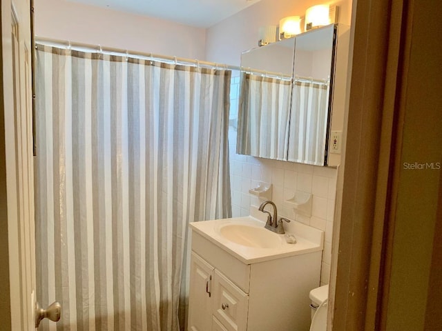 bathroom with vanity, curtained shower, toilet, and decorative backsplash