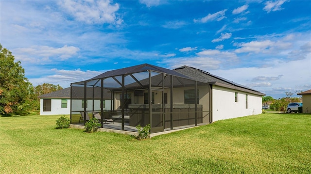 back of property featuring a lawn, glass enclosure, and a patio