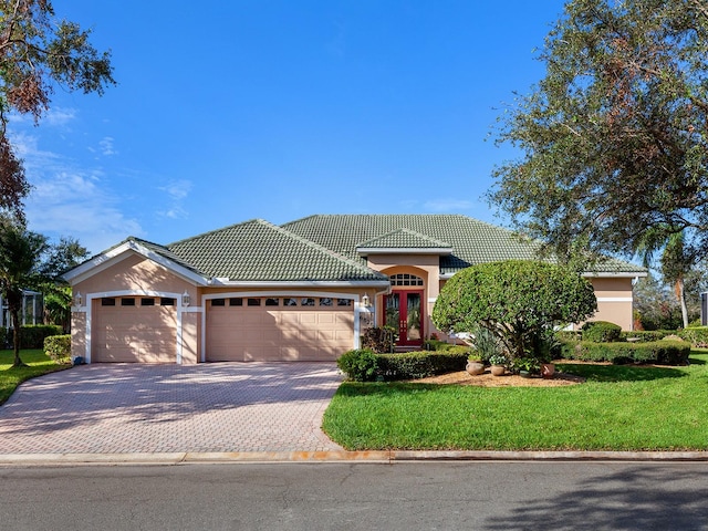 mediterranean / spanish-style house featuring a garage and a front lawn