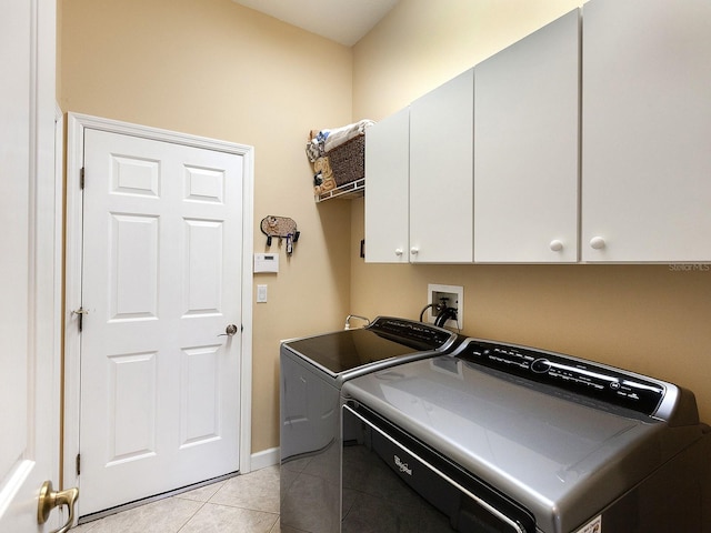 laundry room with cabinets, light tile patterned floors, and washing machine and clothes dryer