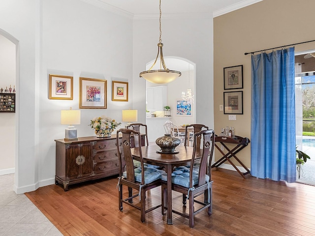 dining area with wood-type flooring, crown molding, and a high ceiling