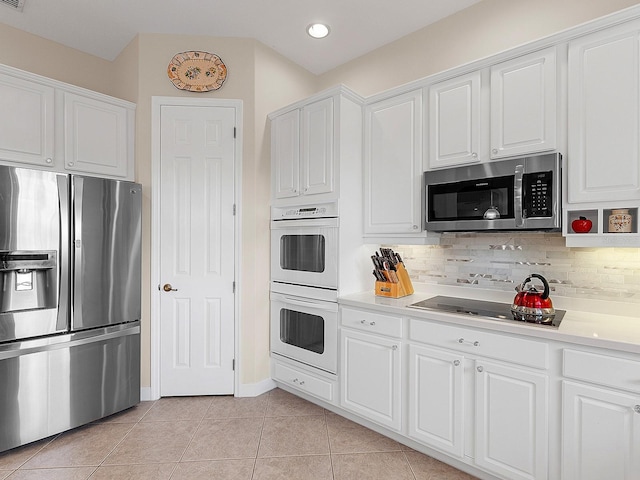 kitchen with decorative backsplash, white cabinetry, light tile patterned flooring, and stainless steel appliances