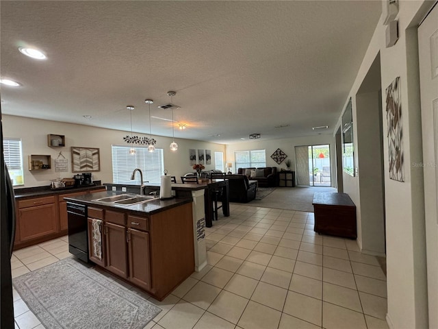 kitchen featuring sink, light tile patterned floors, hanging light fixtures, and a textured ceiling