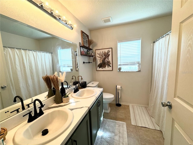 bathroom with tile patterned flooring, vanity, toilet, and a textured ceiling