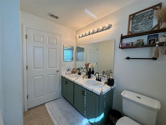 bathroom featuring tile patterned flooring, vanity, a textured ceiling, and toilet