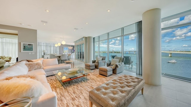 living room with expansive windows, a healthy amount of sunlight, and a water view