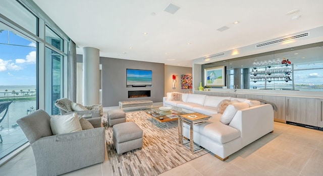 living room featuring light tile patterned floors, a water view, plenty of natural light, and expansive windows