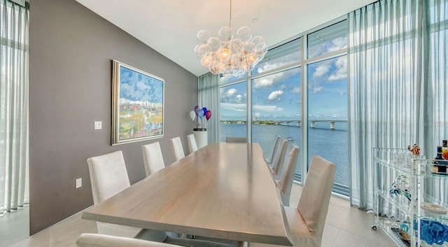 dining room with a water view, a chandelier, and light tile patterned floors