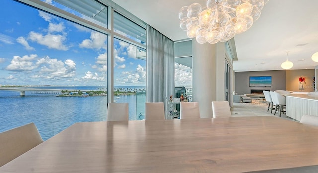 dining room featuring a notable chandelier, expansive windows, and a water view