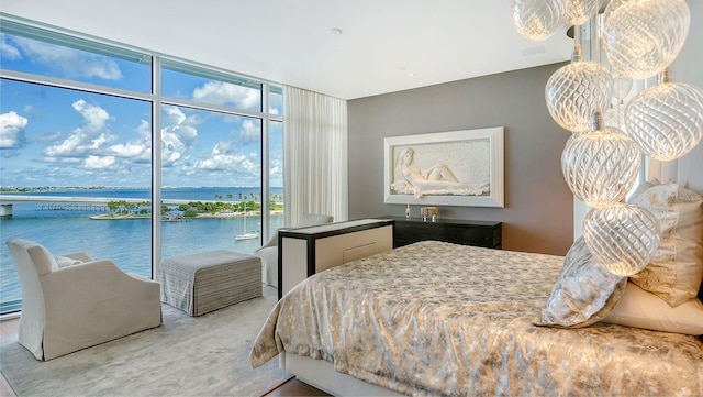 bedroom featuring carpet, expansive windows, a water view, and access to outside