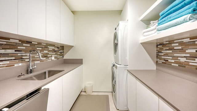 washroom featuring cabinets, stacked washer and dryer, and sink