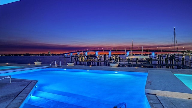 pool at dusk featuring a water view