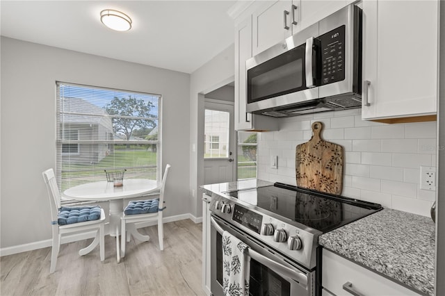 kitchen with white cabinetry, light hardwood / wood-style flooring, light stone countertops, and appliances with stainless steel finishes