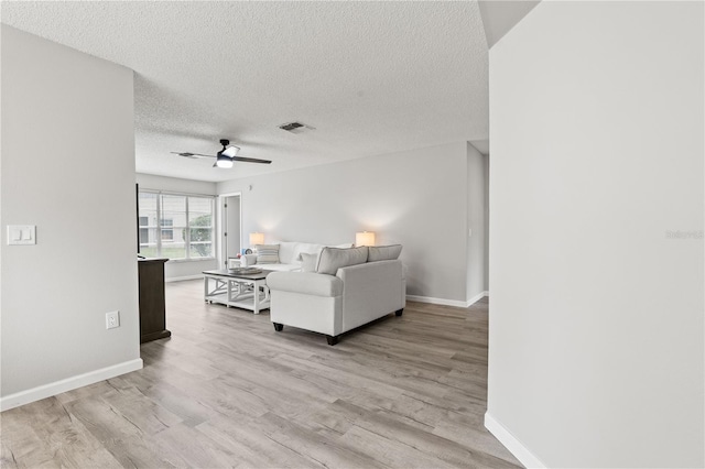 living room with a textured ceiling, light hardwood / wood-style flooring, and ceiling fan