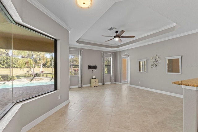 tiled empty room featuring a raised ceiling, ceiling fan, and crown molding