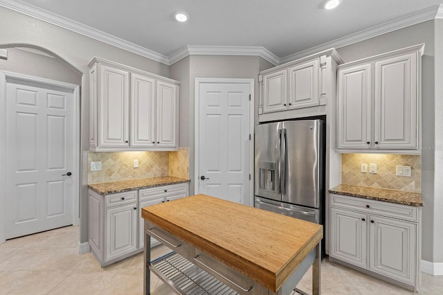 kitchen with stone countertops, ornamental molding, and backsplash