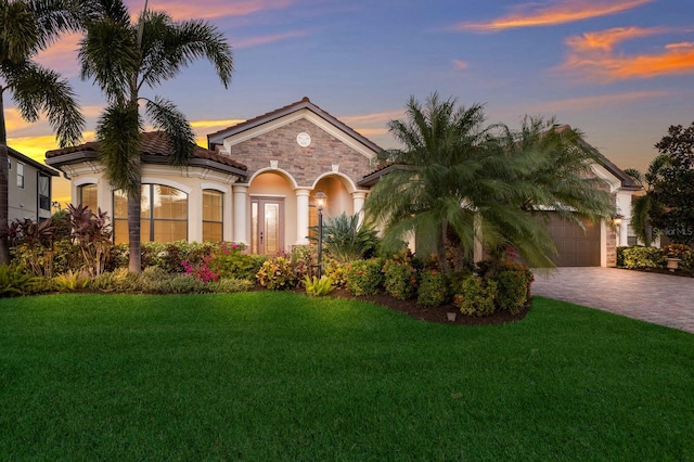 mediterranean / spanish house featuring a garage and a lawn