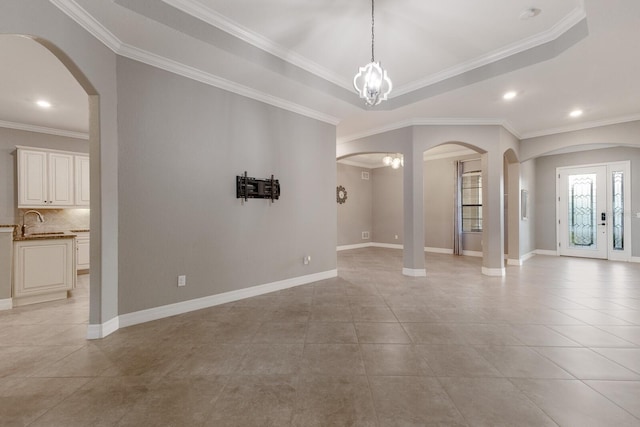 tiled spare room with a raised ceiling, a notable chandelier, sink, and crown molding