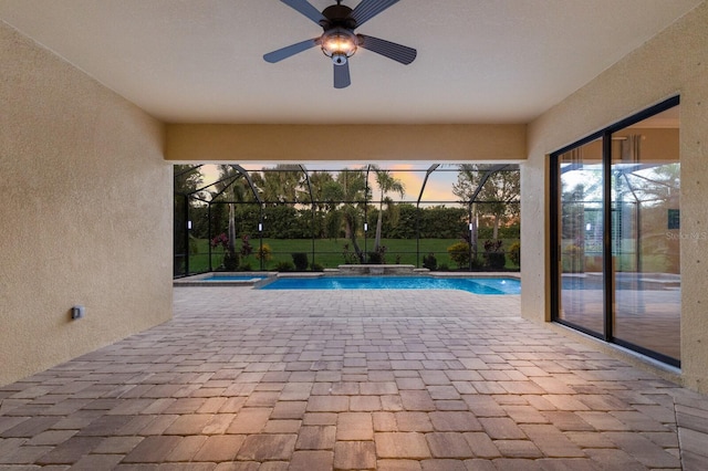 pool at dusk with glass enclosure, an in ground hot tub, a patio area, and ceiling fan