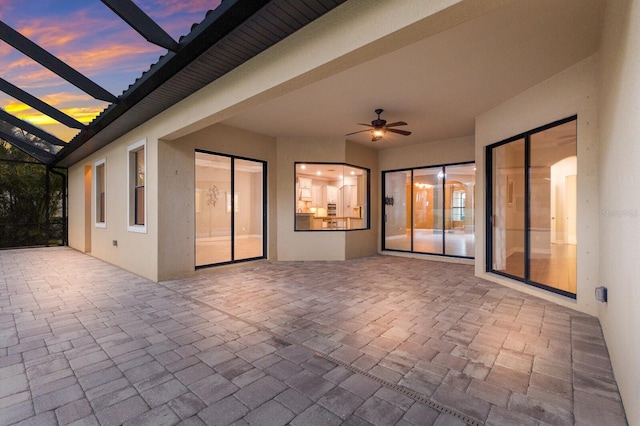 patio terrace at dusk with ceiling fan and a lanai