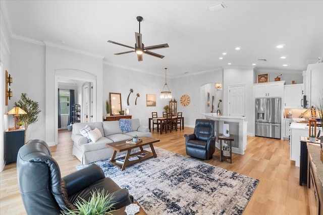 living room with ceiling fan, light wood-type flooring, and ornamental molding