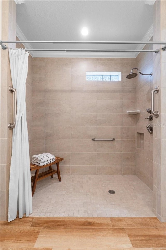 bathroom featuring hardwood / wood-style flooring, crown molding, and walk in shower