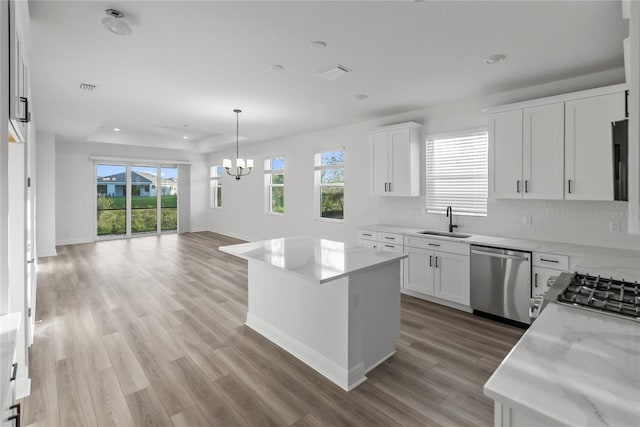 kitchen with white cabinetry, sink, stainless steel appliances, a kitchen island, and light wood-type flooring