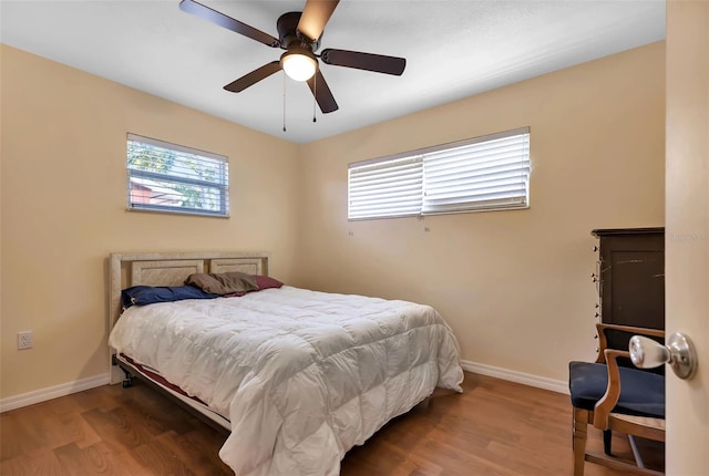 bedroom with multiple windows, ceiling fan, and wood-type flooring