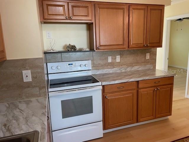 kitchen featuring decorative backsplash, light hardwood / wood-style flooring, and white electric stove