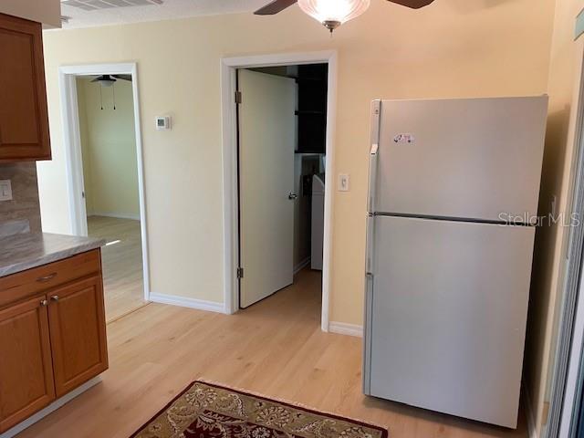 kitchen featuring backsplash, ceiling fan, light hardwood / wood-style flooring, and white fridge