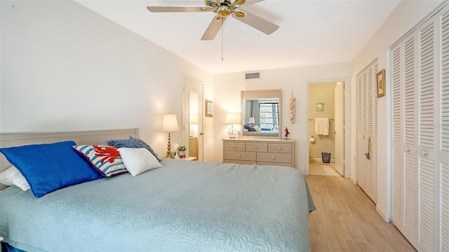 bedroom featuring ceiling fan, light hardwood / wood-style floors, and multiple closets