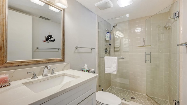 bathroom featuring vanity, toilet, and a shower with door