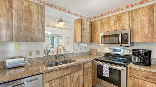 kitchen with light stone countertops, appliances with stainless steel finishes, and sink