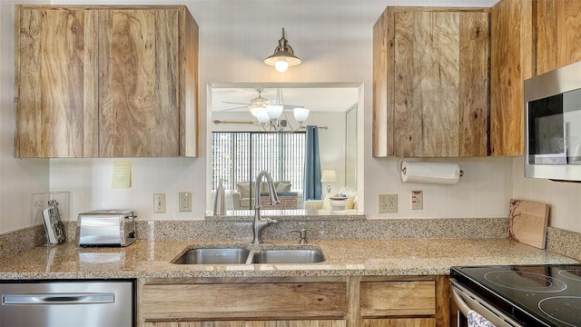 kitchen featuring stainless steel appliances, light stone counters, and sink