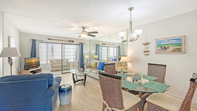 dining room featuring ceiling fan with notable chandelier, a textured ceiling, and light hardwood / wood-style flooring