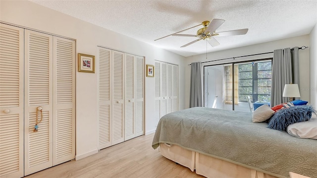 bedroom with light wood-type flooring, a textured ceiling, access to outside, two closets, and ceiling fan