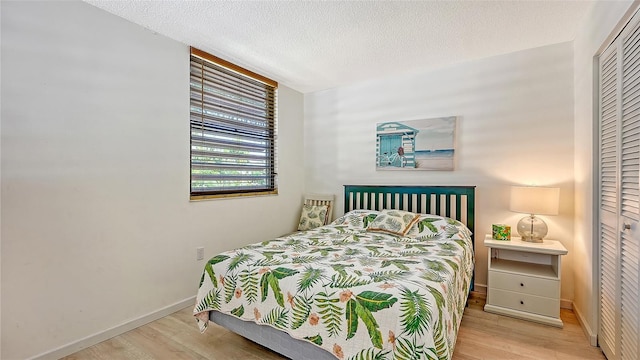 bedroom featuring a textured ceiling, light hardwood / wood-style flooring, and a closet