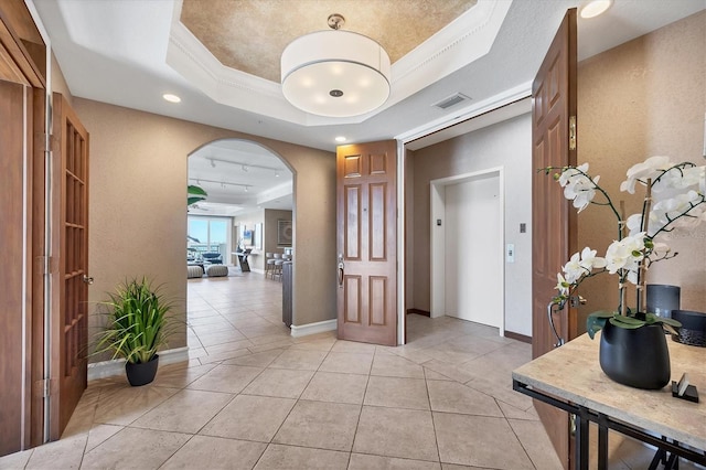 hallway with light tile patterned floors, elevator, a raised ceiling, and crown molding