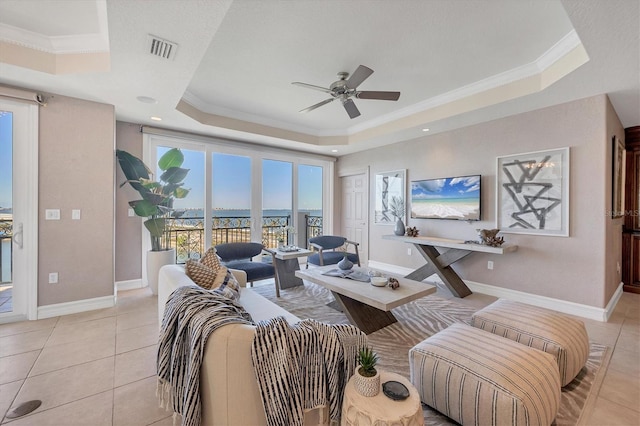 living room with ceiling fan, light tile patterned flooring, crown molding, and a tray ceiling