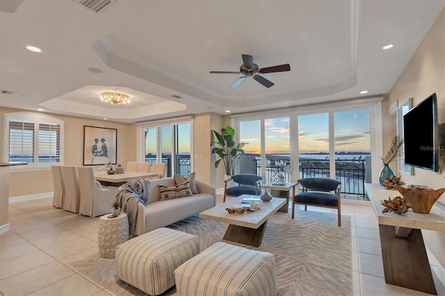 tiled living room featuring a raised ceiling, ceiling fan, and ornamental molding