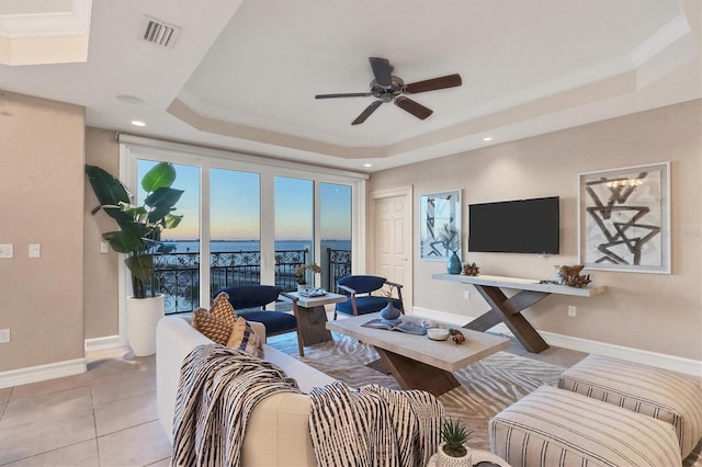 tiled living room with a tray ceiling, ceiling fan, and crown molding