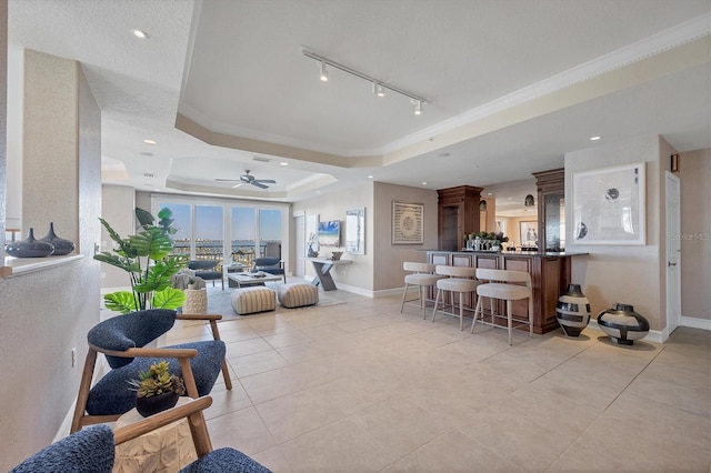 interior space with bar, a raised ceiling, ceiling fan, and crown molding