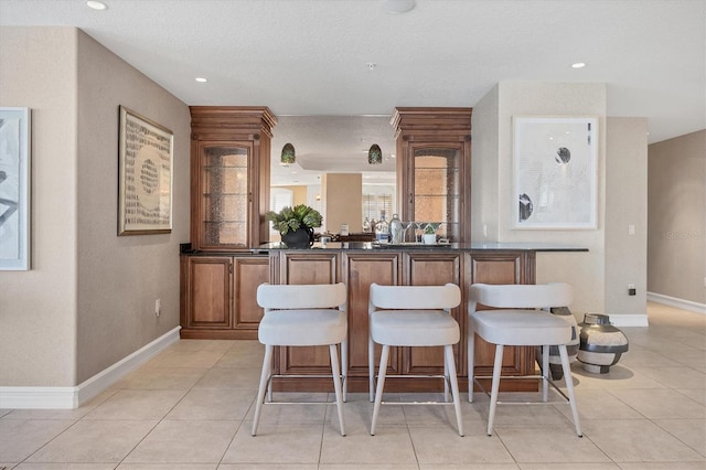 kitchen featuring a breakfast bar, light tile patterned floors, and a textured ceiling