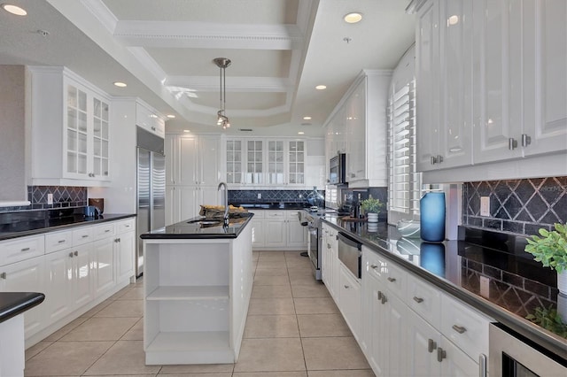 kitchen with sink, stainless steel appliances, backsplash, a center island with sink, and white cabinets